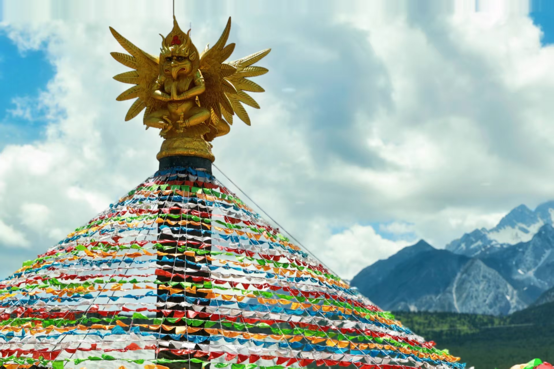 Prayer flags and a golden ornament framed by the mountains of Lijiang