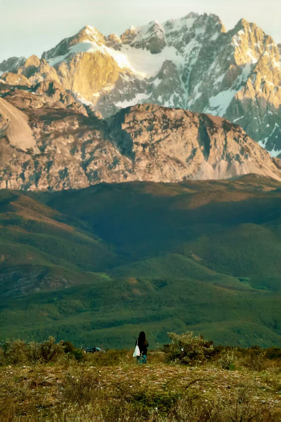 A distant hiker facing a mountain range in Lijiang